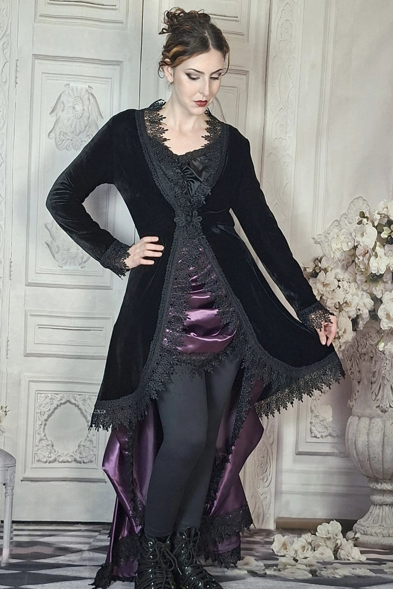 Woman in a black and purple Victorian-style outfit standing in an elegant room.