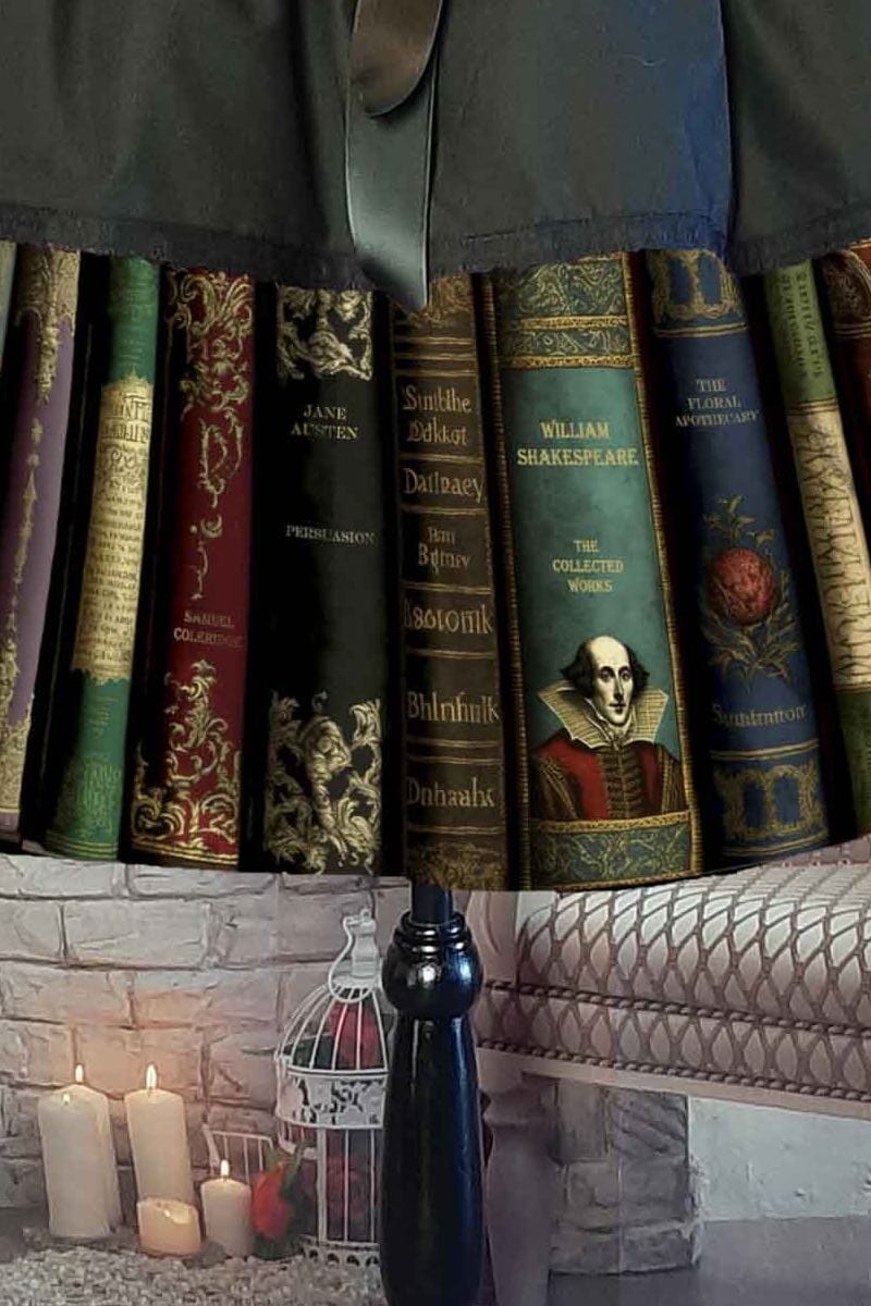 close up on the book spine print of the Dark Academia themed midi length full skirt made from black polycotton with a print of famous classic works of fiction, showing the spines of the books, colours are dark greens, dark reds, blacks and gold featuring William Shakespeare, Jane Austen