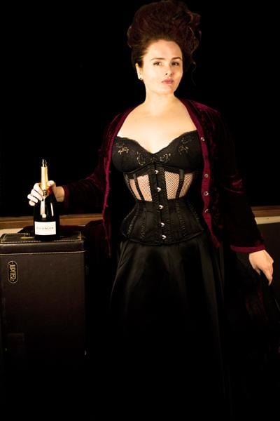 new dark desire black mesh corset worn by corset model Elizabeth Smyth during a quarantine photo shoot front view with bottle of Bollinger