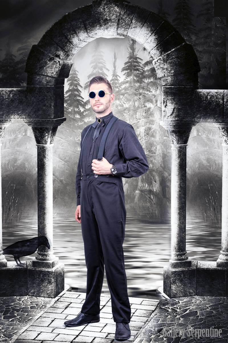 darker Edgar Allan Poe style imagery in background of the model in the black Tombstone high waisted old wild west men's trousers made of wool blend, worn here with black button on suspender braces