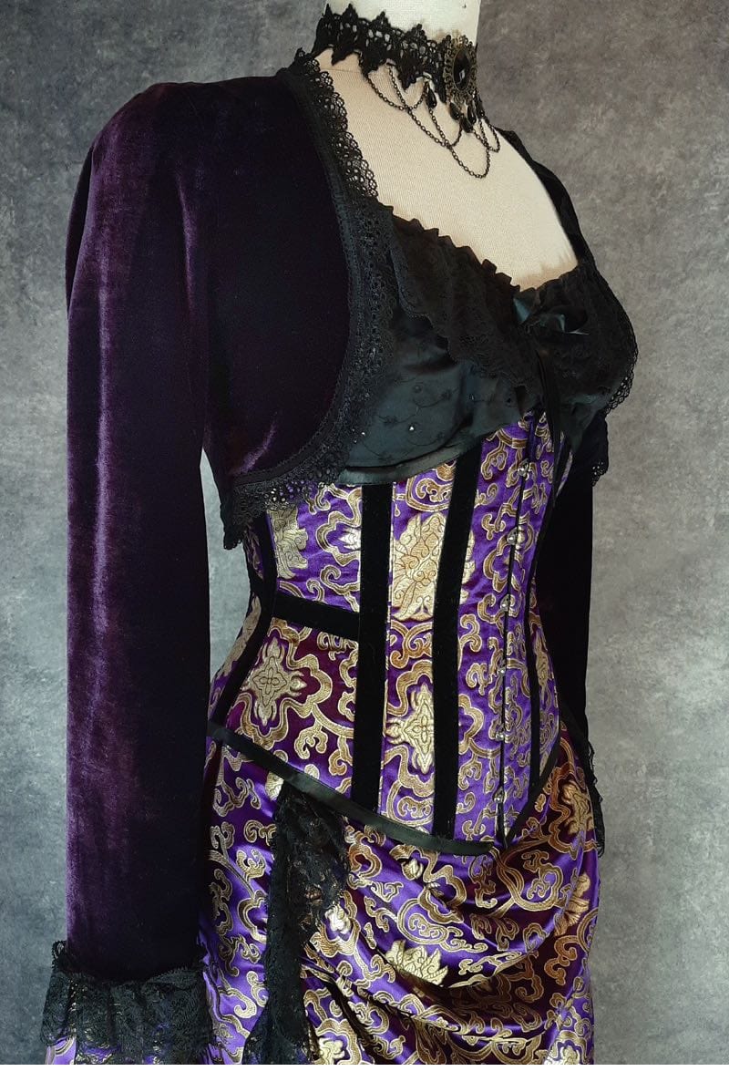 side front view of the purple stretch velvet bolero shrug showing the sleeve and how it sits just over the side of an under bust corset