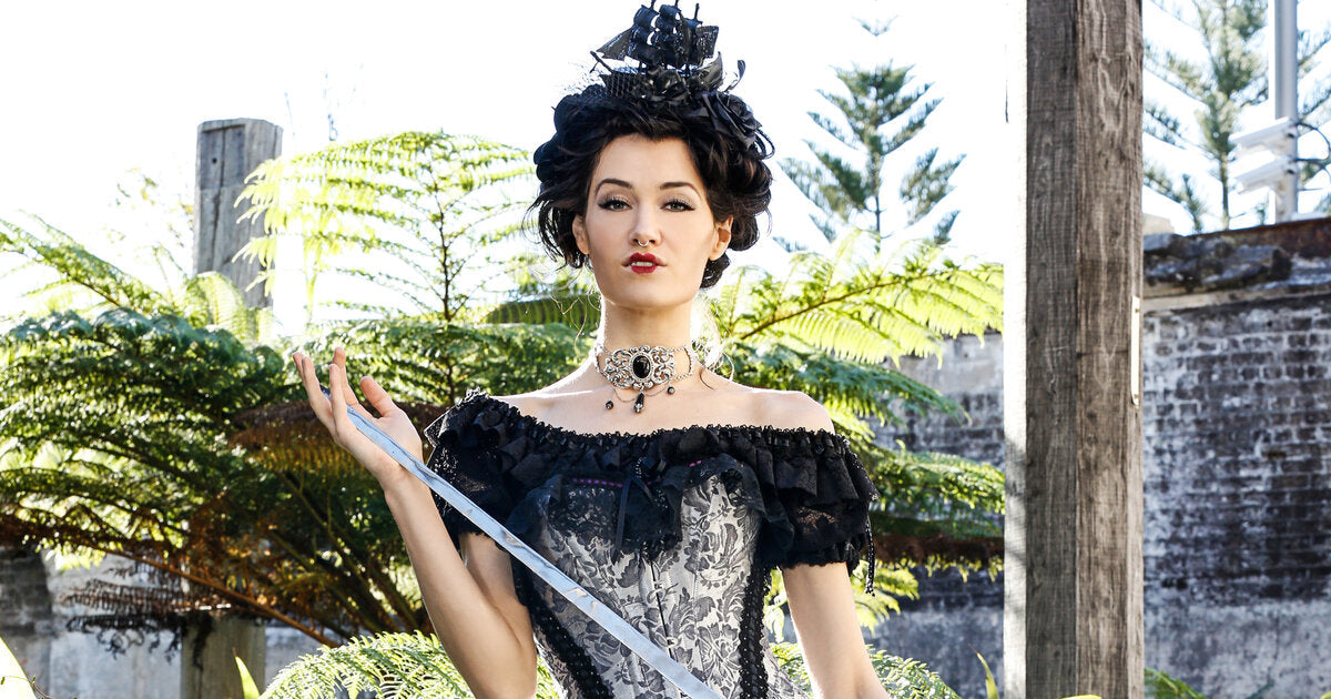 medieval queen wearing silver Gallery Serpentine corset gown, carrying a long sword