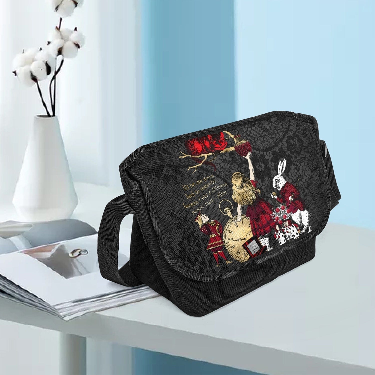 gothic Alice in Wonderland Messenger Bag made from canvas with a gothic gold, red and white Alice in Wonderland character print against a black lace print background, shown at a waiting room office