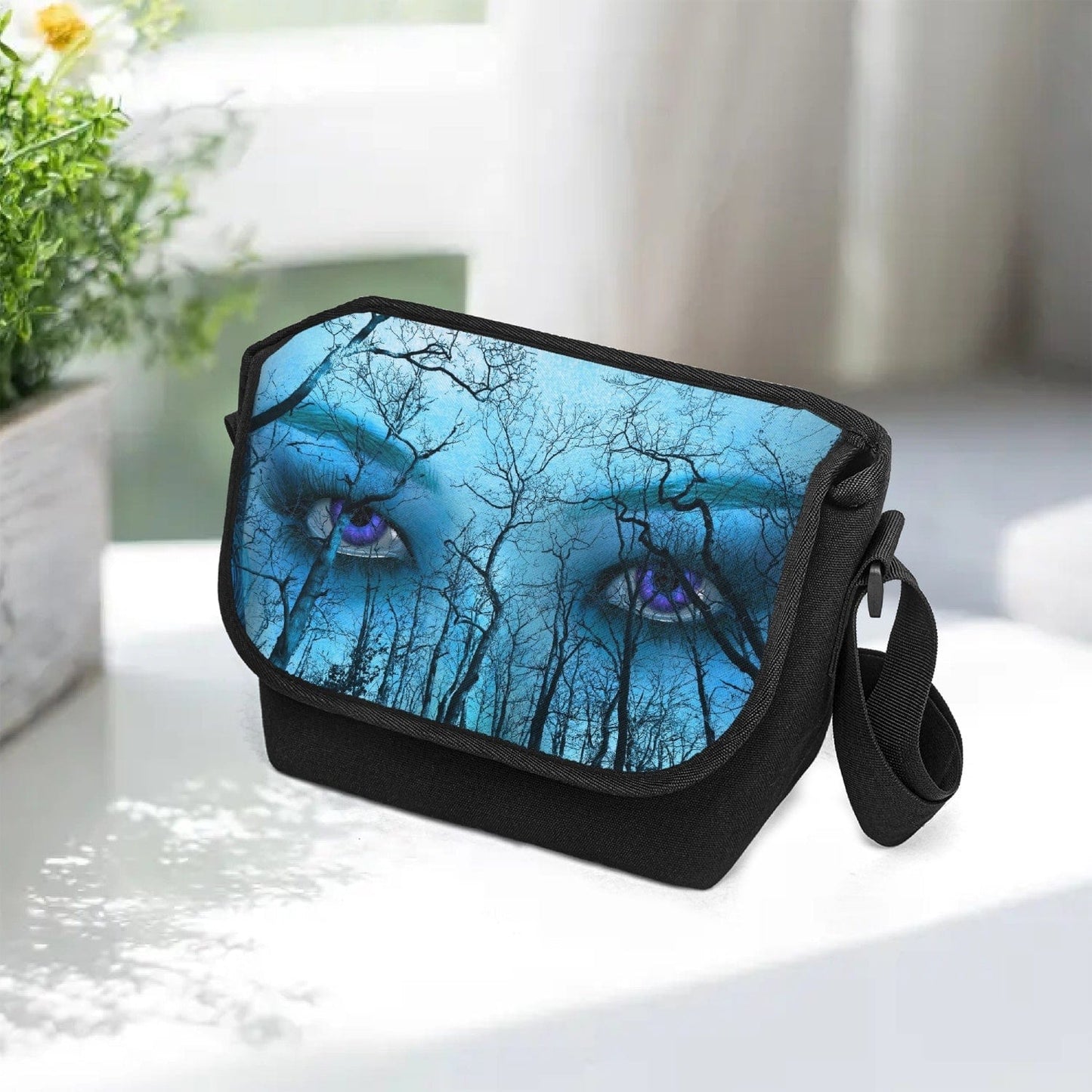 Piercing purple eyes feature on a forest themed print on this canvas messenger bag at Gallery Serpentine.  Blue and aqua tones give this a supernatural feel with a gothic naturecore theme 4
