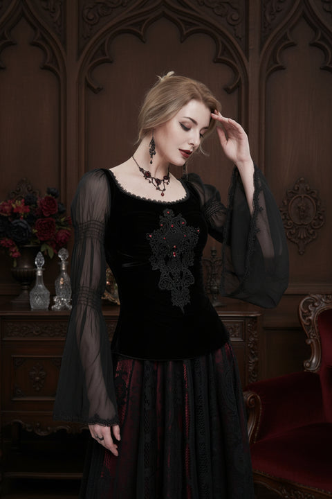 Woman wearing a black lace top with sheer bishop sleeves in a victorian parlour setting of dark wood panelling