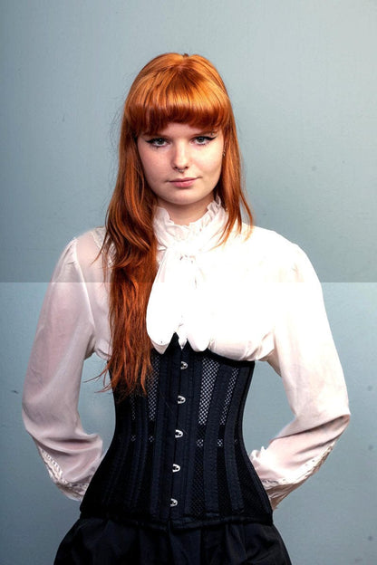 Keeva, red head wears the LONGLINE Waist Control Corset that is double steel boned, made from heavy duty mesh and cotton with her corporate white shirt and black skirt