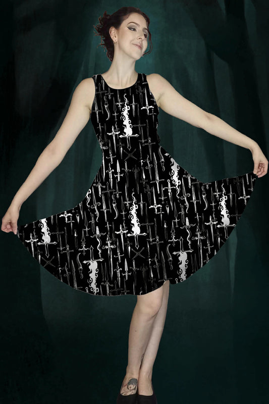 Woman wearing a black dress with white dagger & flames patterns against a dark green enchanted forest background