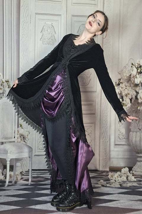 Woman in a black and purple dress with floral decorations in an elegant room.