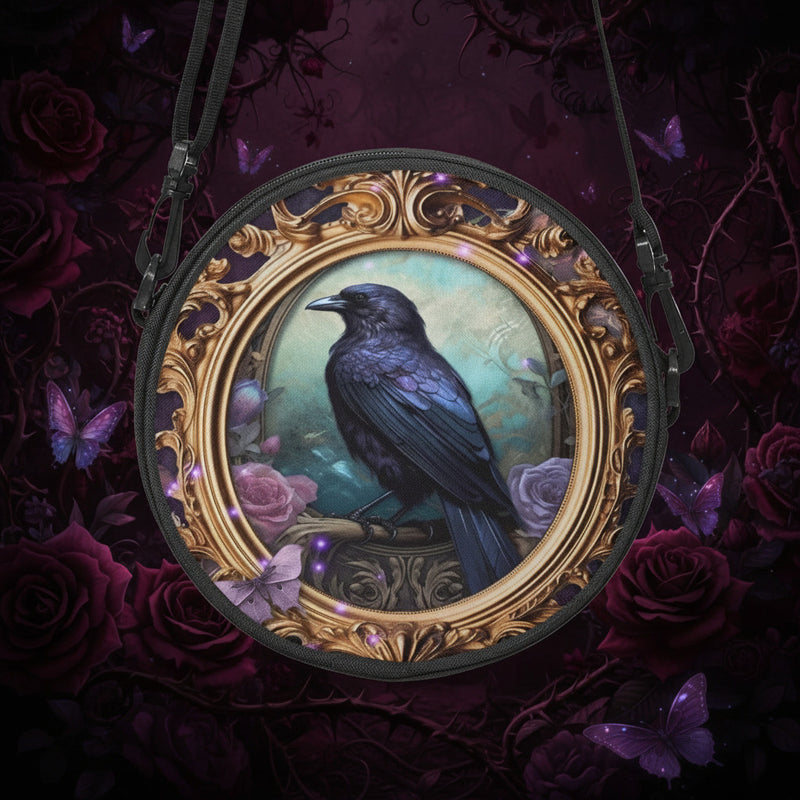 glossy black raven perched inside a gold rococo gilt frame features as the art work on this 23cm diameter round canvas cross body bag
