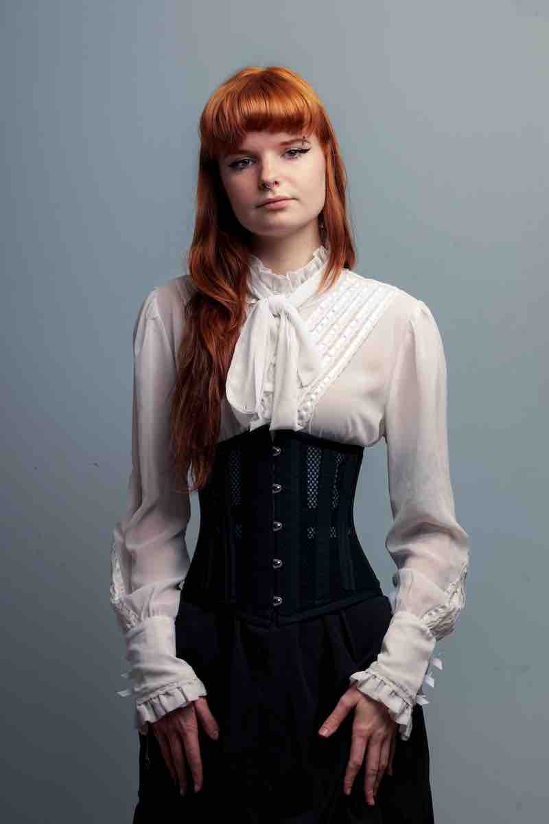 young red headed corporate woman wearing the White Victorian blouse with a posture correcting corset from Gallery Serpentine
