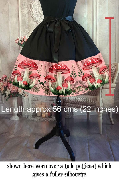 red toadstools on a vintage pink background on a 50s shaped mid length cottagecore, mushroomcore skirt with overlaid text showing skirt length of 56cms