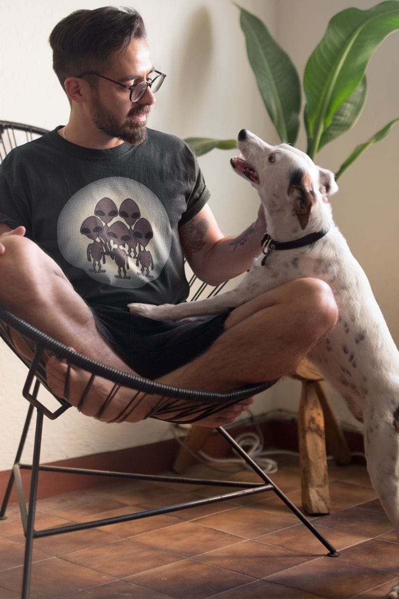 Man wearing the We Came to TikTok Alien men's t-shirt with a very cute friendly white spotted dog