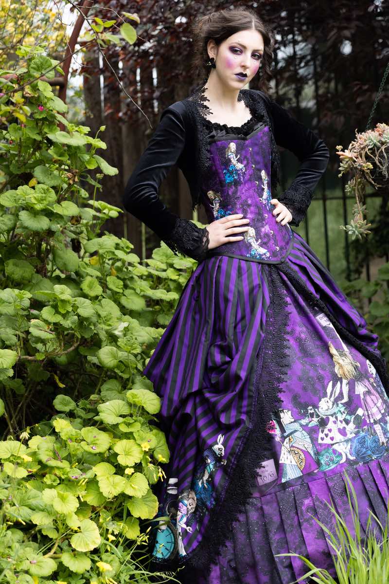 fashion model wearing the gothic victorian Alice in Wonderland gown by Gallery serpentine in purple and black