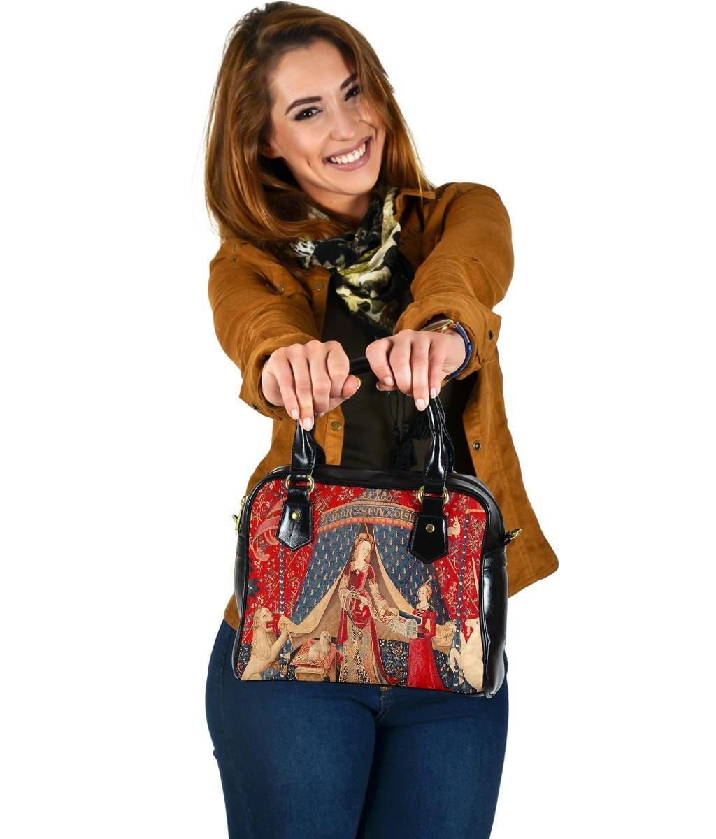 woman showing the viewer the red, blue, gold colours in the The Lady & the Unicorn medieval tapestry artwork printed on a vegan leather women's handbag