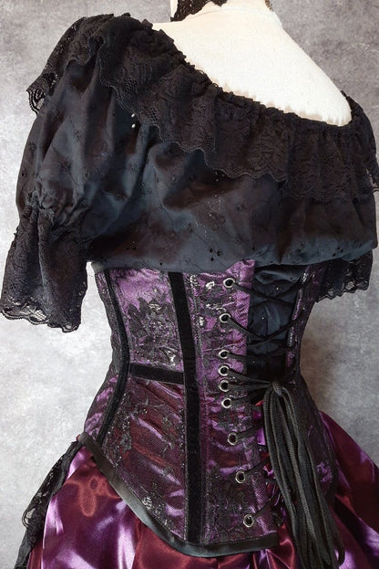 back side view showing lacing cord & eyelets on the amethyst satin with black lace overlay and black velvet ribbon on the bone channels on a mannequin torso with under bust top in black