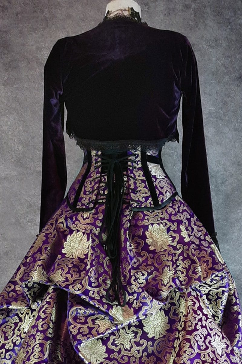 back view of the purple stretch velvet Bolero Shrug worn over a purple & gold corset and victorian skirt