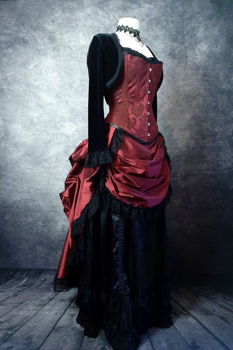 front side view showing the kirtle front drape of the deluxe length victorian bustle skirt in garnet taffeta worn over a black satin under skirt and bustle cage