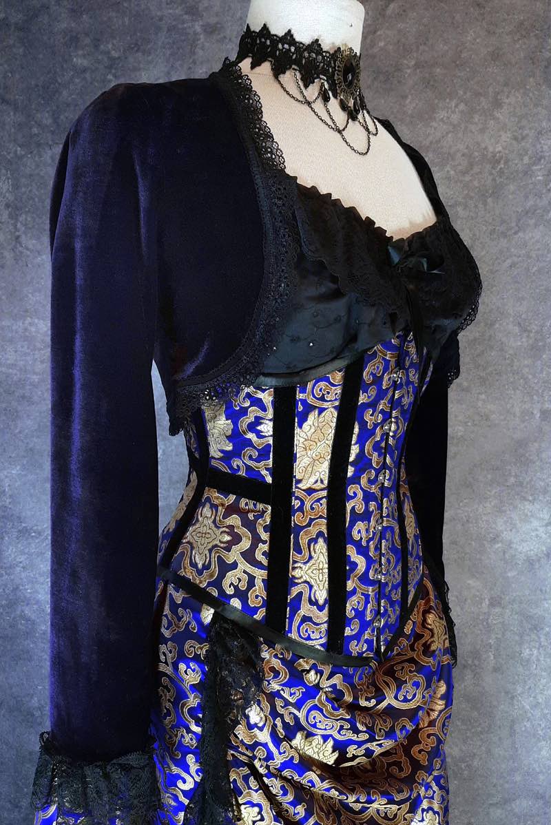 side view showing the black velvet trim down the bone channels of the royal blue and gold brocade under bust corset by Gallery Serpentine