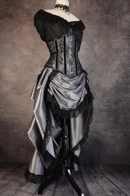 full length side front view showing the matching silver bustle skirt in the Australian made under bust tight lacing corset in a dark silver taffeta overlaid with delicate black lace and trimmed with black velvet ribbon down the corset bone channels