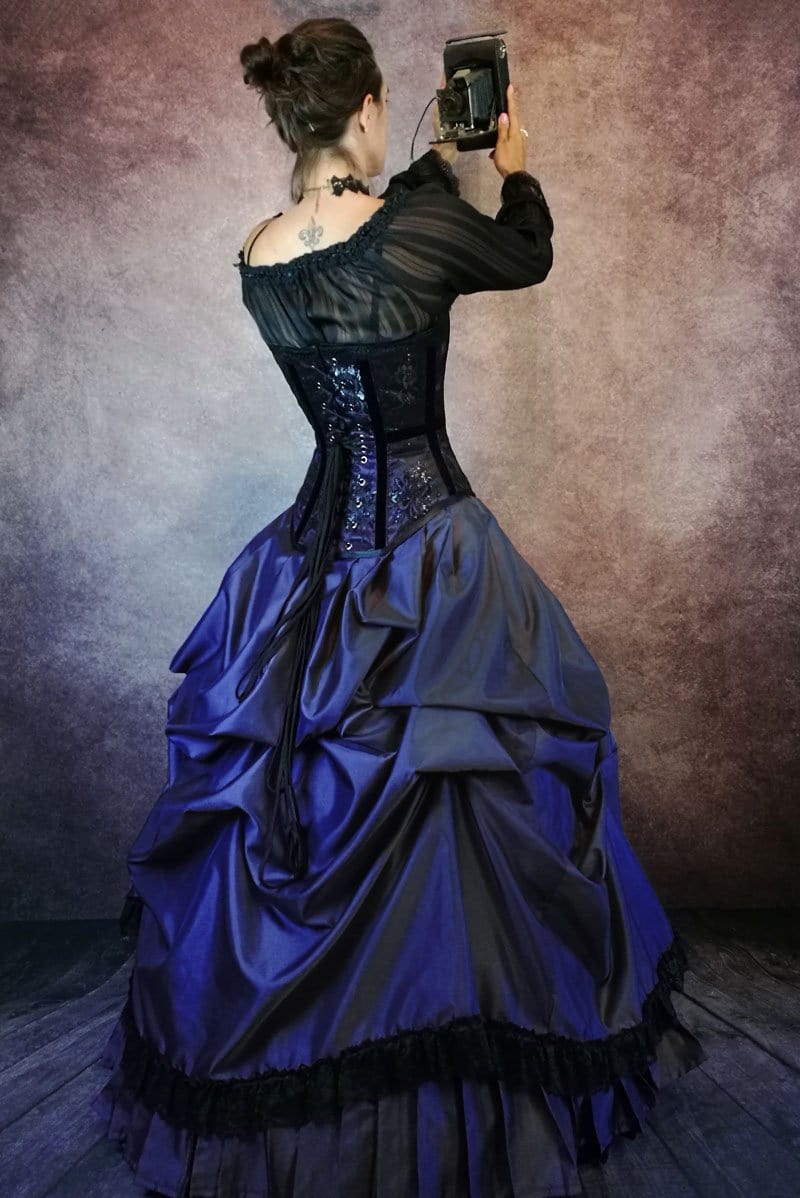 model in victorian ball gown with steel boned corset and vintage camera