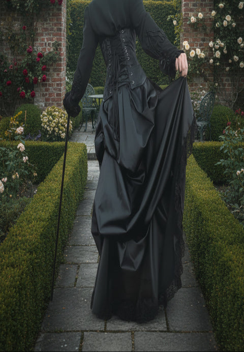 victorian woman shows the volume of fabric in the gothic victorian black sateen lace trimmed high low bustle skirt with adjustable waist sizing made in Australia for Gallery Serpentine